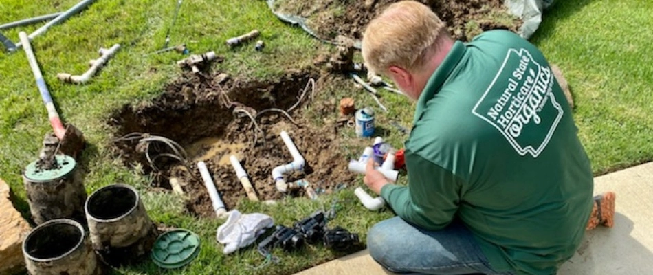 Irrigation specialist repairing broken pipe from irrigation system in Little Rock, AR.