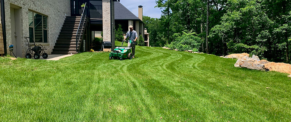 Lawn care worker using core aeration equipment in North Little Rock, AR.